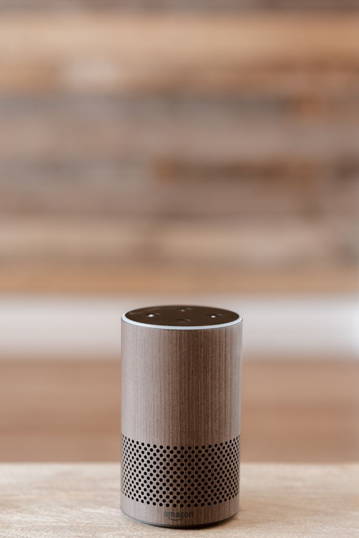 who-we-are Une enceinte intelligente posée sur une surface en bois, sur fond flou, mettant en valeur un design minimaliste.